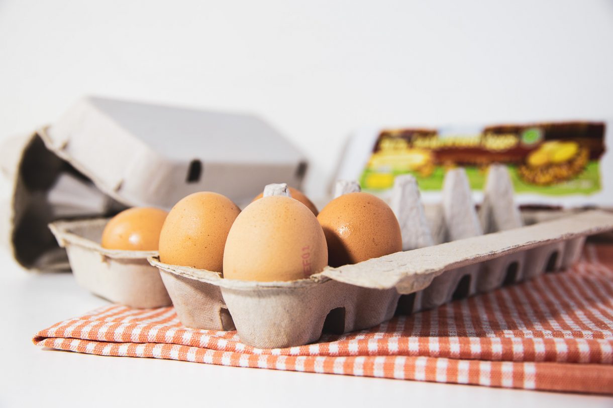 Carton Packaging egg carton open with eggs more cartons in the back ground